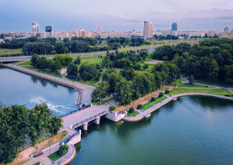 Obraz na płótnie Canvas Aerial view of Minsk cityscape and a pedestrian bridge in the Victory Park in the city center