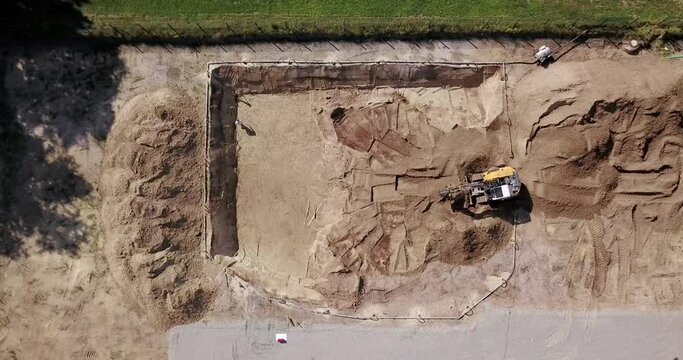 Bagger auf einer Baustelle hebt eine Baugrube aus. Tiefbau, Erdbau aus der Vogelperspektive