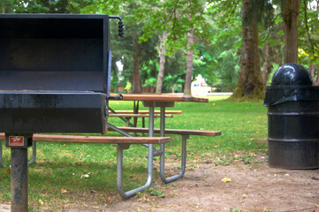 A campground BBQ grill and garbage can