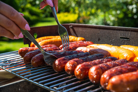 Grilling sausages. The concept of resting in the fresh air, frying sausages on the grill. Arranged sausages, barbecue.