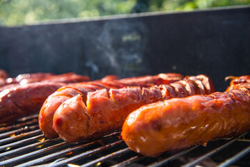 Grilling sausages. The concept of resting in the fresh air, frying sausages on the grill. Arranged sausages, barbecue.