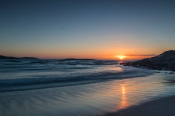 Fototapeta na wymiar Warm, calm and beautiful sunset on the virgin beach of Barra, Ponteceso. The waves move smoothly
