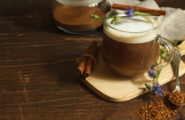  cappuccino from chicory root, decorated with cinnamon and flower, on a dark wooden background, horizontal with space