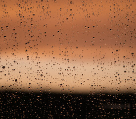 raindrops on window pane while sunset