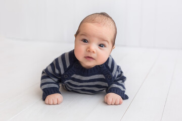 Fototapeta premium baby in a striped jacket on a white background. a three-month-old boy. children's photo session
