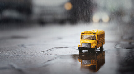 Yellow school bus (toy model) during hard rain fall in city,low angle view and shallow depth of...