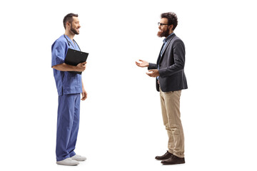 Full length profile shot of a bearded man talking to a male doctor in a blue uniform