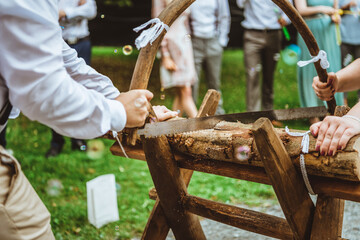 Wedding. Bride and groom sawing a log