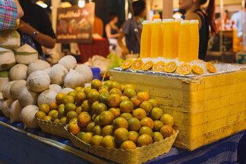 Fresh fruit tangerine and tangerine juice in bottle at night food market in Bangkok, Thailand. Eco organic street food concept.