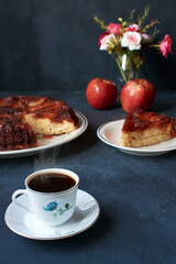 apple pie with kitchen cutlery and coffee on a dark base with natural light