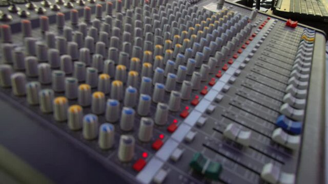 audio sound mixer, hand moving slides and knobs, music equipment