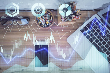Double exposure of financial graph hologram over desktop with phone. Top view. Mobile trade...