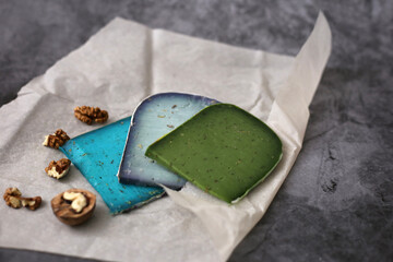 Pesto cheese slices with lavender and basil. Blue and green cheese on gray background