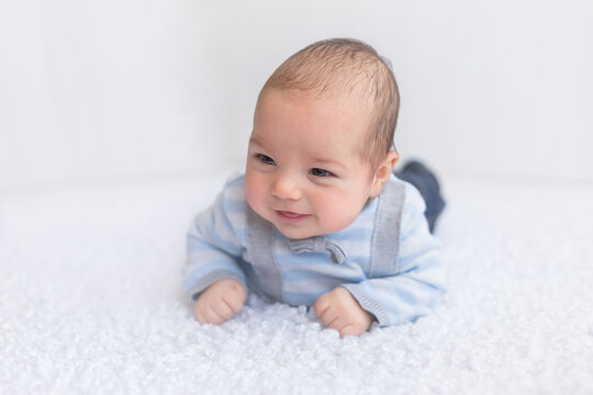 baby in a striped jacket on a blue background. a three-month-old boy. children's photos