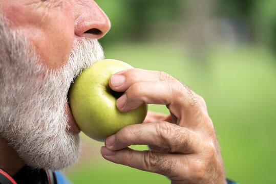 Senior sportsman eating green apple