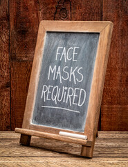 face masks required - white chalk handwriting on a blackboard, coronavirus covid-19 pandemic concept