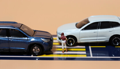 Miniature people and miniature cars. A concept about warning of the risk of using a Smartphone when crossing a crosswalk.
