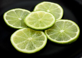 Fototapeta na wymiar GREEN LEMON citrus aurantifolia AGAINST BLACK BACKGROUN