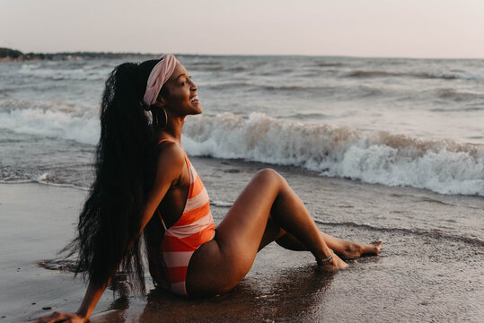 Two african american female friends swimming and laughing at the beach