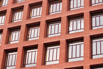 Fototapeta na wymiar Urban texture and pattern. Architecture. Closeup view of the building facade. The apartment windows and the red brick wall. 