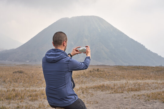 Man visiting Bromo volcano by jeep and using a mobile phone