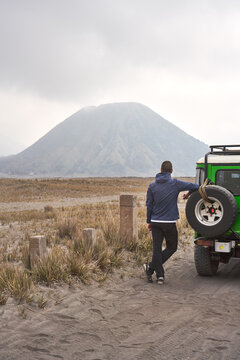 Man visiting Bromo volcano and Leaning To a jeep