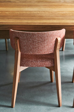 Chair with pink seat at wooden table