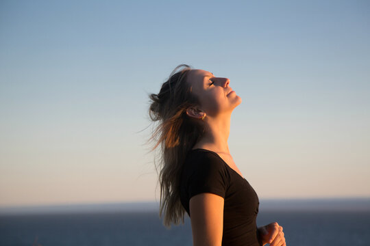 Beautiful teen by the ocean at sunset