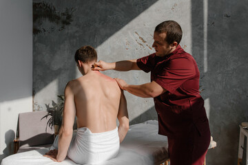 Brunet man lying on table on scraping massage session.