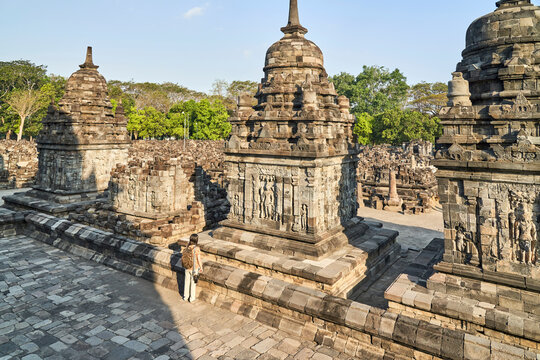Back view of woman with backpack looking at a hindu carving in Prambanan Temple, Java, Indonesia