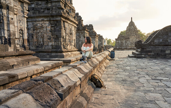 Woman with backpack enjoying the sunset in Prambanan Temple, Java, Indonesia