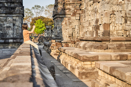 Woman using cell phone to take pictures in Prambanan Temple, Java, Indonesia