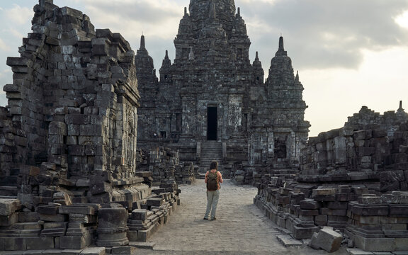 Back view of woman with backpack standing in the path to a temple in Prambanan Temple, Java, Indonesia
