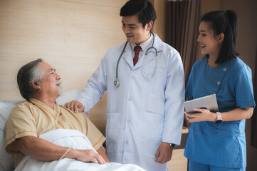Obraz premium Surgeon doctor with digital tablet visiting senior male patient in hospital bed at geriatric unit