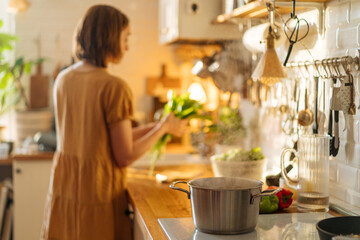 Woman preparing greenery for boiling soup