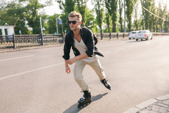 a man on roller skates quickly rides in the backlight with cars on the road