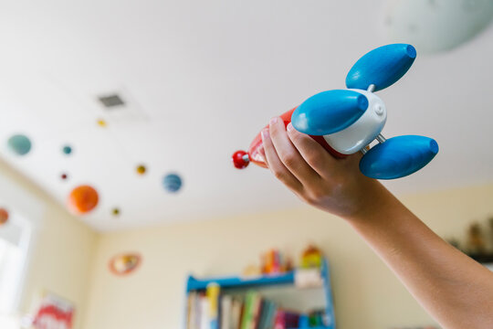 Hand of Child Playing with Toy Rocket Ship and Solar System Mobile