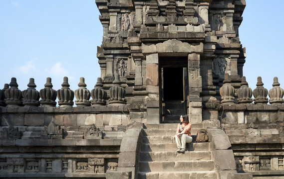 Woman with backpack sitting at the steps of the temple's entrance. in Prambanan Temple, Java, Indonesia