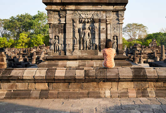 Back view of woman looking at a hindu carving in Prambanan Temple, Java, Indonesia