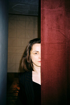 Young Woman Hidden Behind A Red Curtain