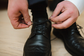 the guy‚Äôs hands are tying shoe laces