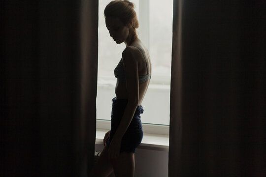 girl in underwear is standing silhouette by the window