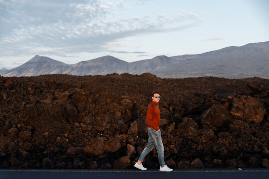 &radic;&ecirc;&not;&uml;an in red sweater on roadside with mountains on background&radic;&euml;&not;&eacute;