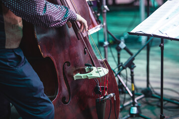 Concert view of a contrabass violoncello player with vocalist and musical during jazz orchestra band performing music, violoncellist cello player on stage