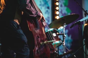 Concert view of a contrabass violoncello player with vocalist and musical during jazz orchestra band performing music, violoncellist cello player on stage