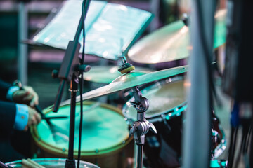 Drummer percussionist performing on a stage with drum set kit during jazz rock show performance, with band performing in the background, drummer point of view