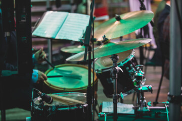 Drummer percussionist performing on a stage with drum set kit during jazz rock show performance, with band performing in the background, drummer point of view