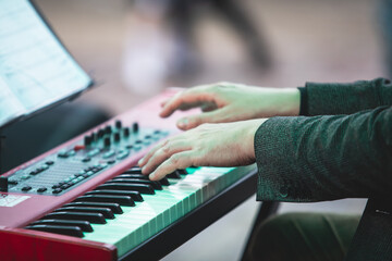 Obraz premium Concert view of a musical keyboard piano player during musical jazz band orchestra performing, keyboardist hands during concert, male pianist on stage, hands close up