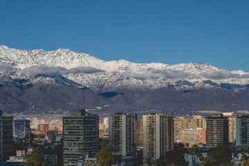 Lonely clouds in the sky over Santiago skyline and the snowed Los Andes mountains, Chile