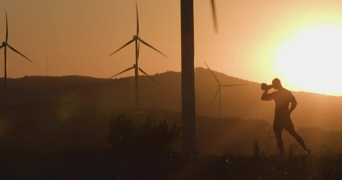 Athlete at sunset trains with a kettlebell. Silhouette shooting. The concept of environmentally friendly energy